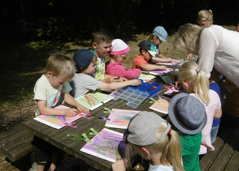 Kinder sitzen am Tisch und malen und basteln